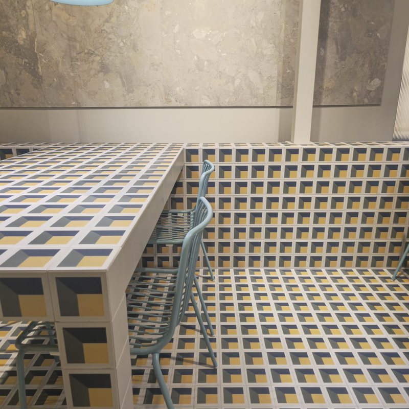 Cersaie 2026 : les tendances carrelage 2027 repérées à Bologne 7 Cersaie 2026, tendances carrelage 2027 chez Piastrella - table et sol habillés du même carrelage géométrique